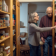 A neatly organized kitchen pantry with labeled containers and shelves filled with various food items, including cereal boxes, jars of pasta, canned goods, and snacks.