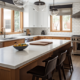 An image of a modern kitchen with sleek finishings, including a marble countertop, stainless steel appliances, and a large island with bar stools. The kitchen is well-lit and features open shelving to display decorative dishes and glassware.