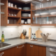 A photo showing a neatly organized kitchen cabinet with labeled containers for various food items such as pasta, rice, and cereals. There are also hanging hooks under the cabinet for utensils and a drawer organizer for cutlery.